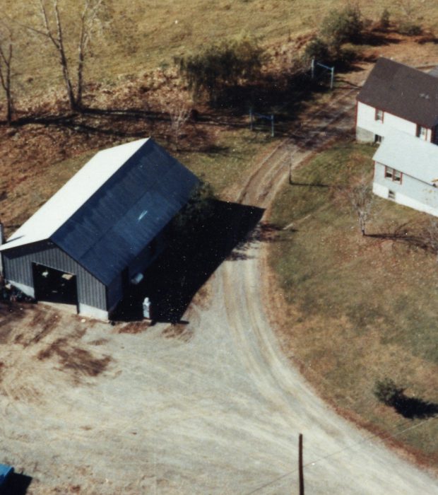 Two large dump trucks drive on a dirt construction site.