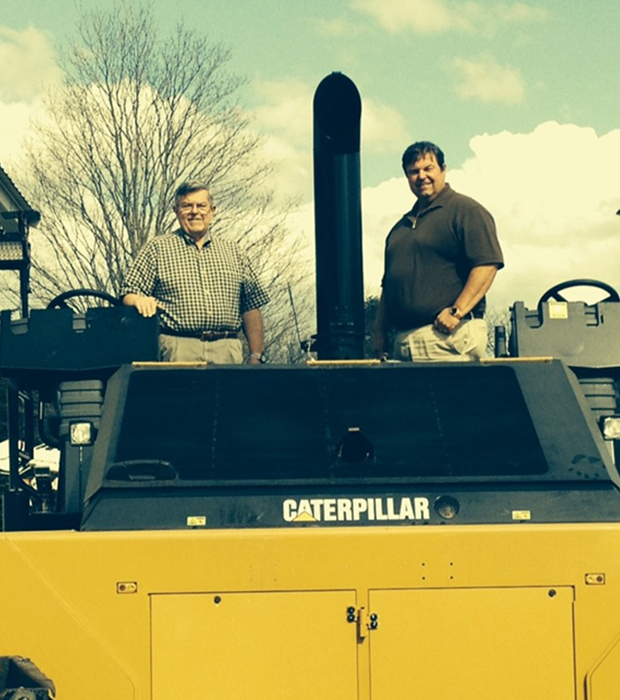 Two large dump trucks drive on a dirt construction site.