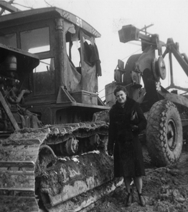 Two large dump trucks drive on a dirt construction site.
