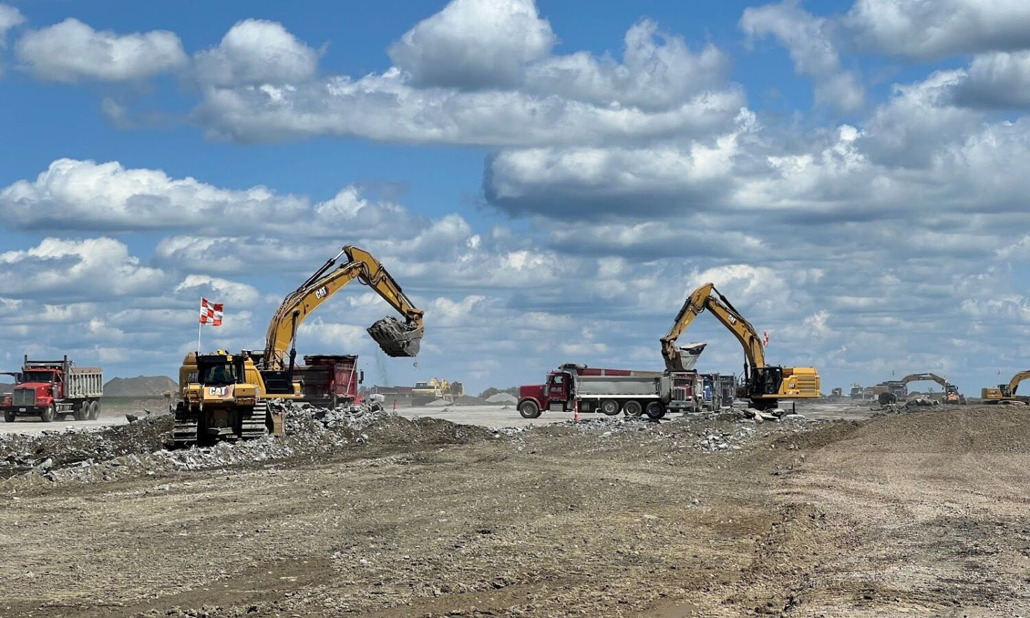 Excavators load rocks into dump trucks at construction site.