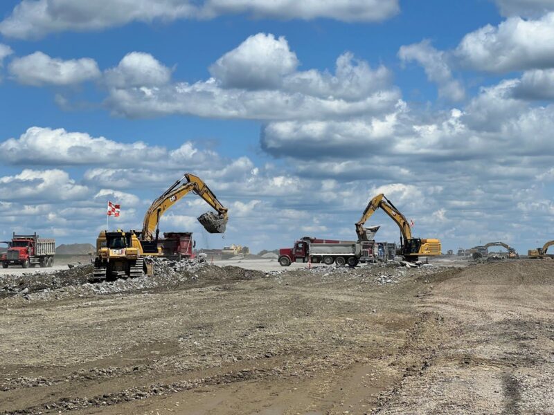 Excavators load rocks into dump trucks at construction site.
