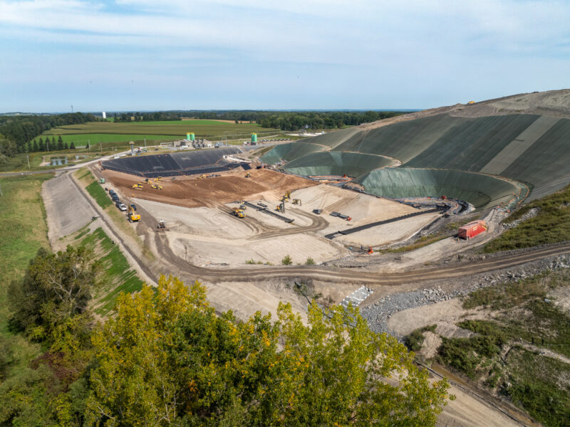 Aerial view: landfill site, machinery, earthmovers, geomembrane liners.