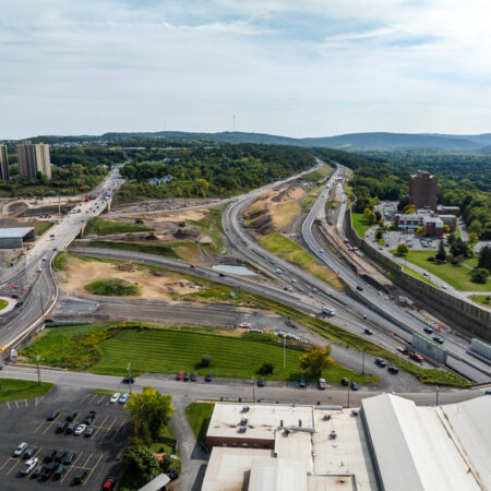 Aerial view of highway construction with roads, roundabout, greenery.