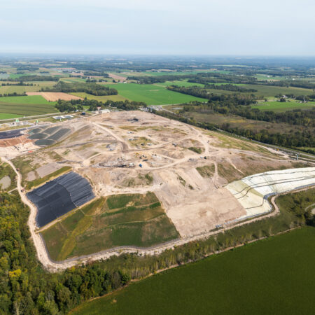 Aerial view of landfill under construction near farmland and trees.
