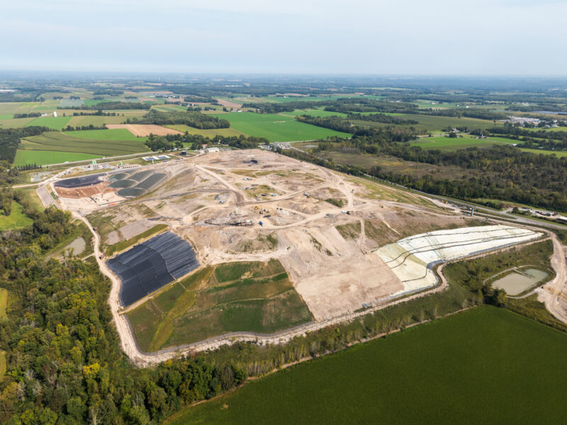Aerial view of landfill under construction near farmland and trees.
