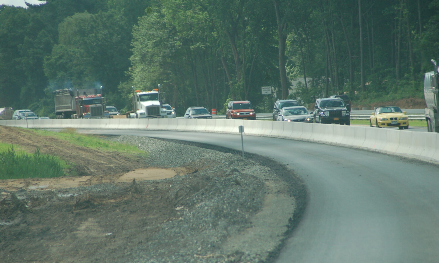 Cars and trucks on divided highway; construction on left side.