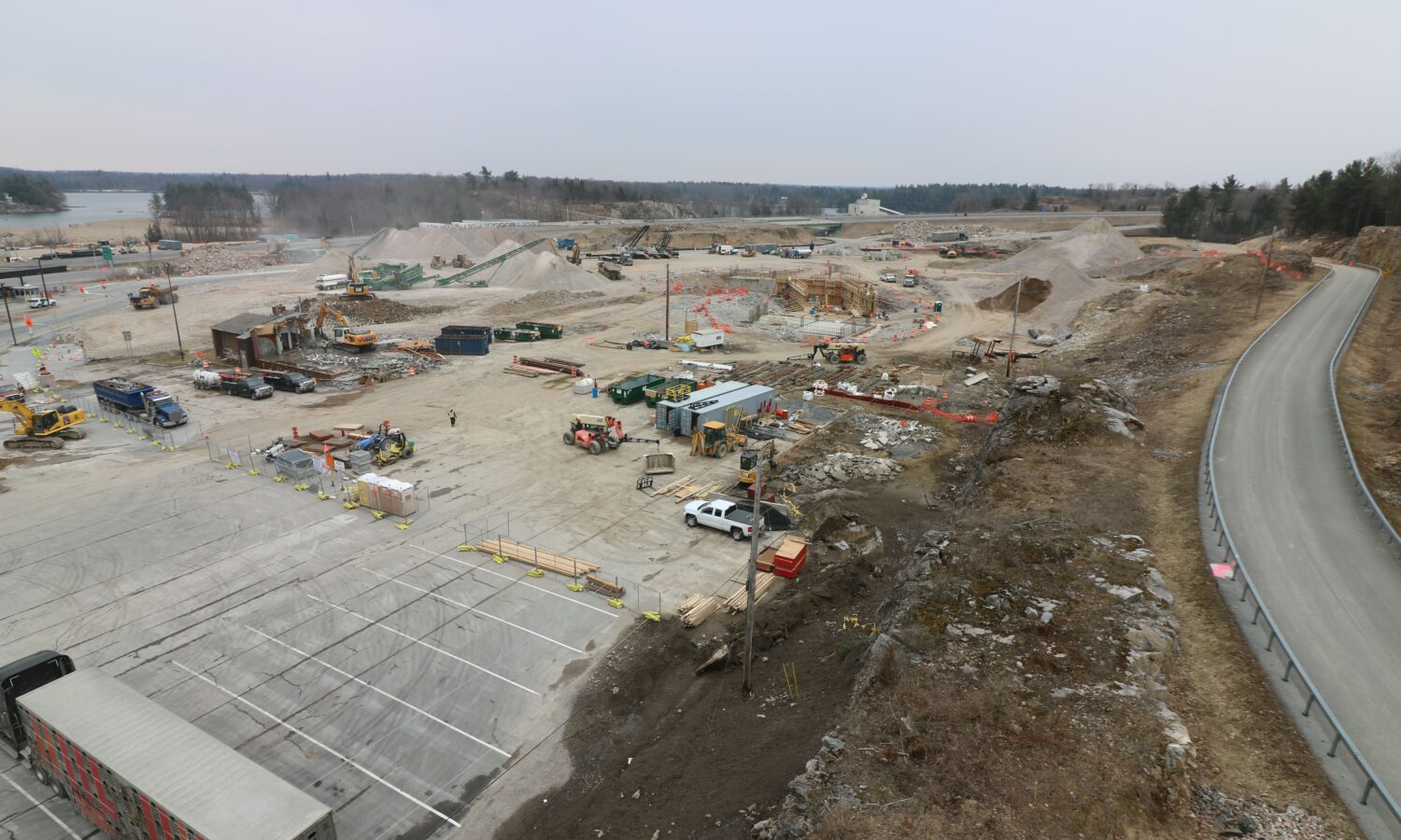 Construction site with machinery, dirt piles, and empty parking lot.