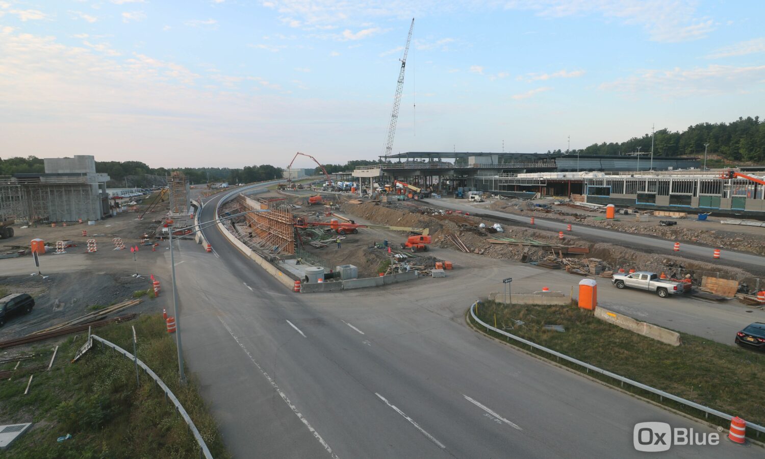 Highway construction with heavy machinery, crane, barriers, and cones.