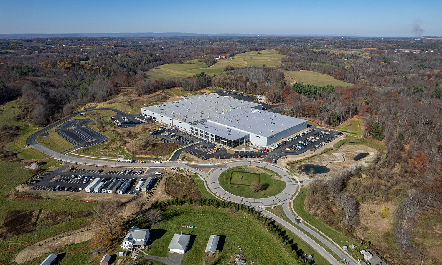 Aerial view of warehouse with parking, roads, and surrounding fields.