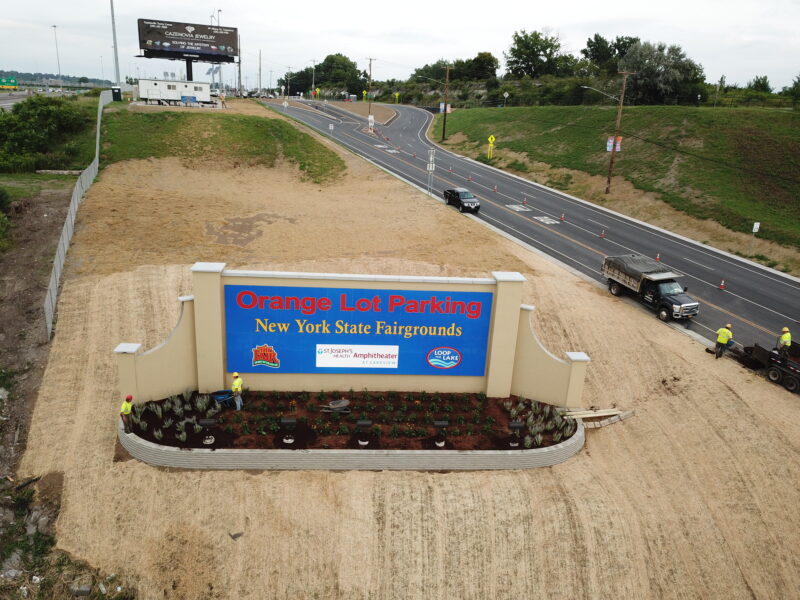Aerial view: Sign for Orange Lot Parking of New York State Fairgrounds on the side of the road.