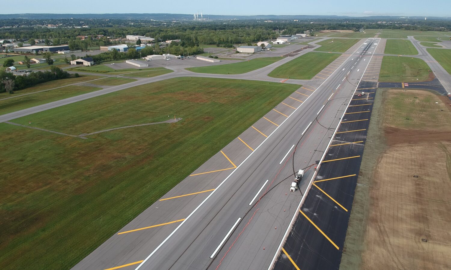 Aerial view of runway construction with vehicles and fresh markings.