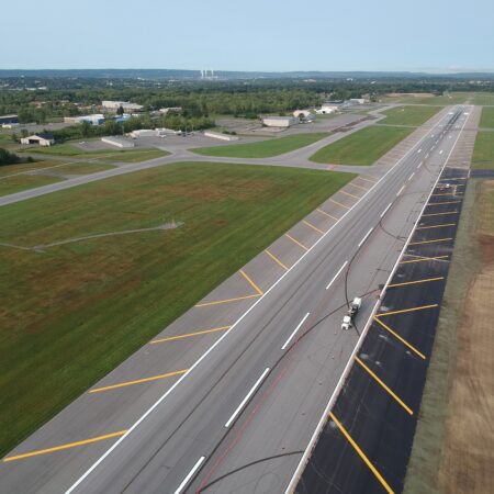 Aerial view of runway construction with vehicles and fresh markings.