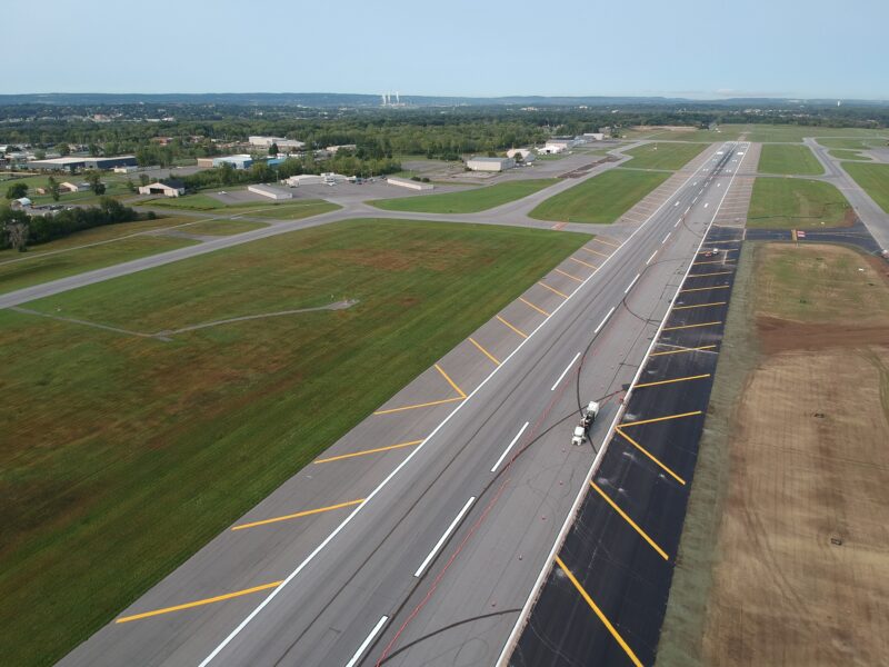 Aerial view of runway construction with vehicles and fresh markings.