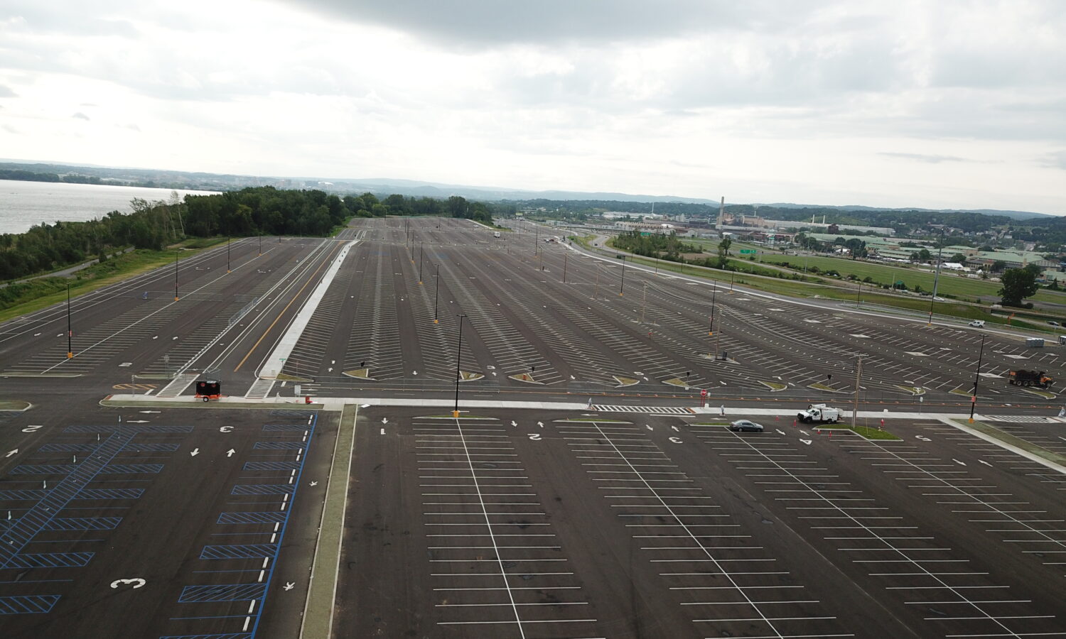 Empty parking lot with marked spaces, few light poles, cloudy.