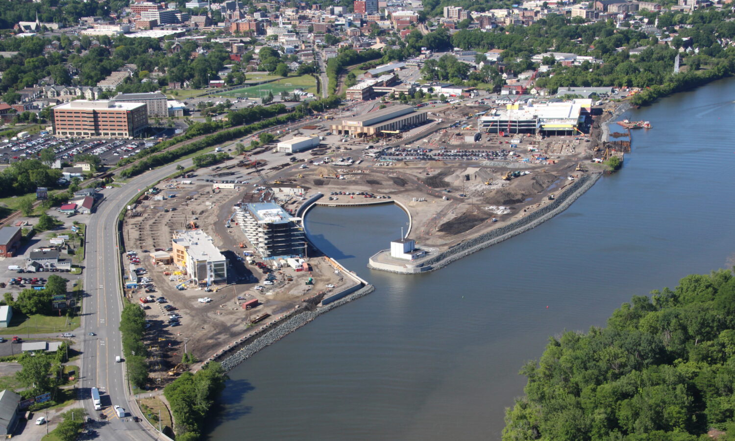 Aerial of waterfront construction, bridge, urban area, and greenery.