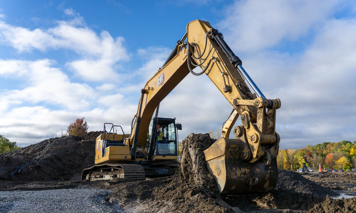 Yellow excavator digs dirt pile at construction site.