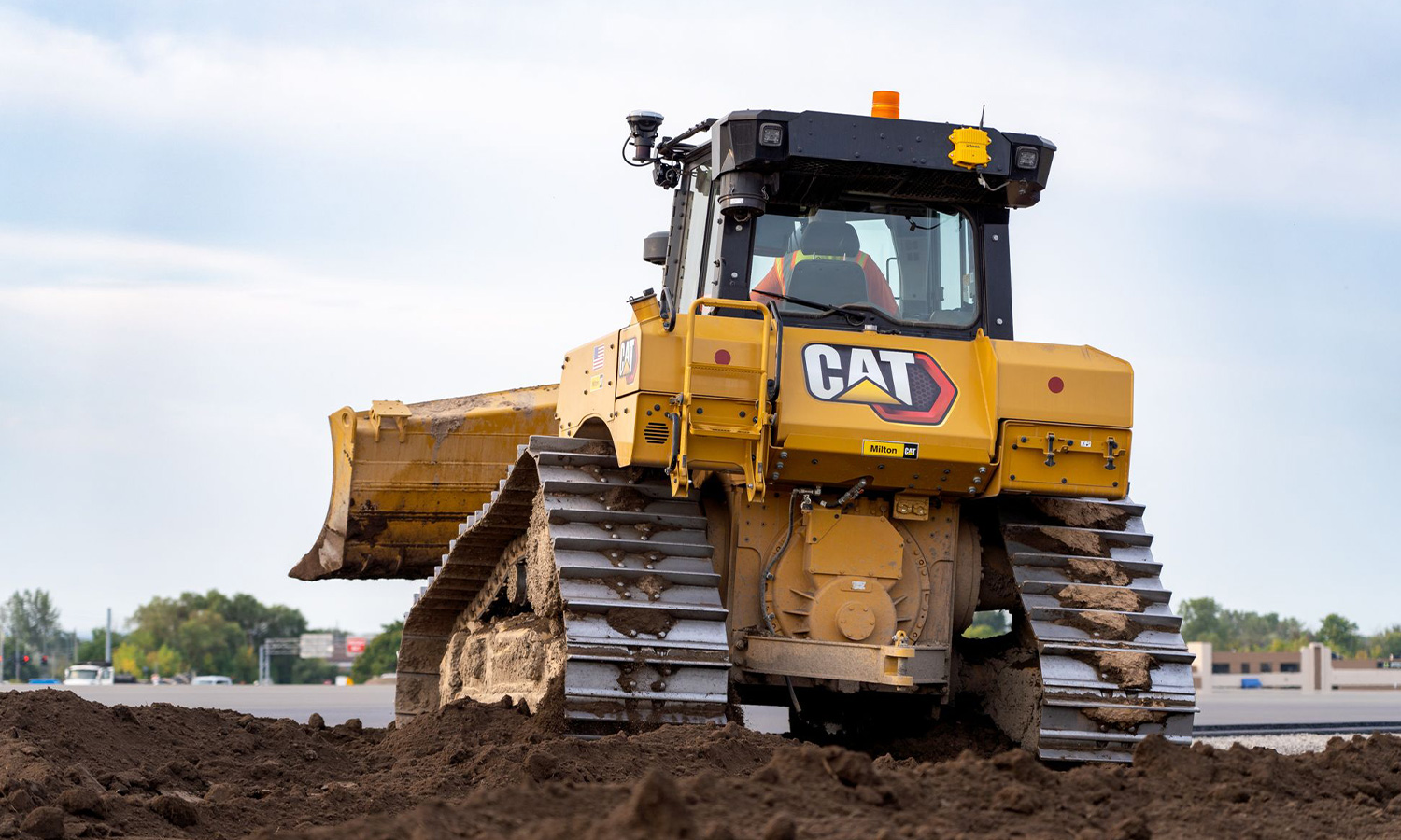 Yellow Caterpillar bulldozer pushes dirt, back view