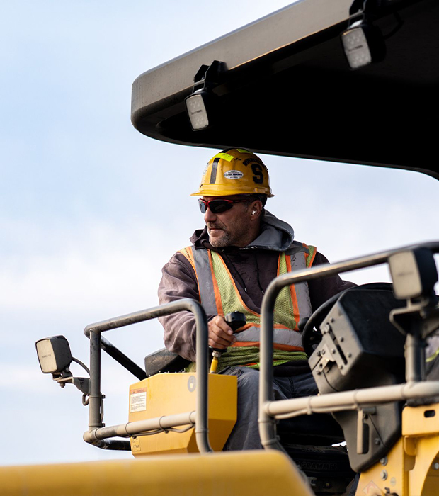 Two workers in safety gear shake hands in a grassy field