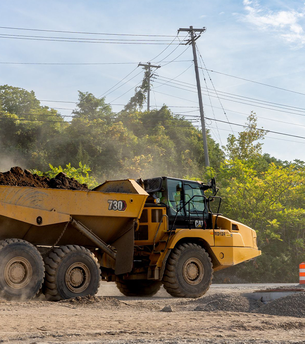 Two yellow bulldozers grade soil on a sloped site.